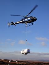 Image of a helicopter airlifting sphagnum beads onto site 